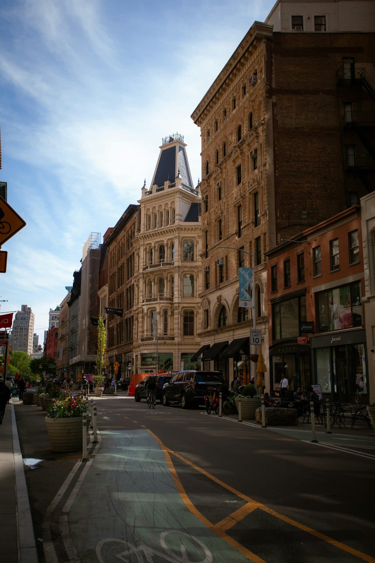 A city street lined with historic pre-war apartment buildings at golden hour